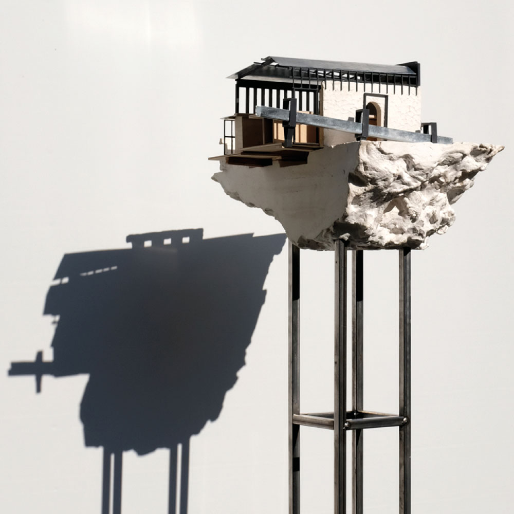 A render of a building on a piece of rock, on a metal stand.