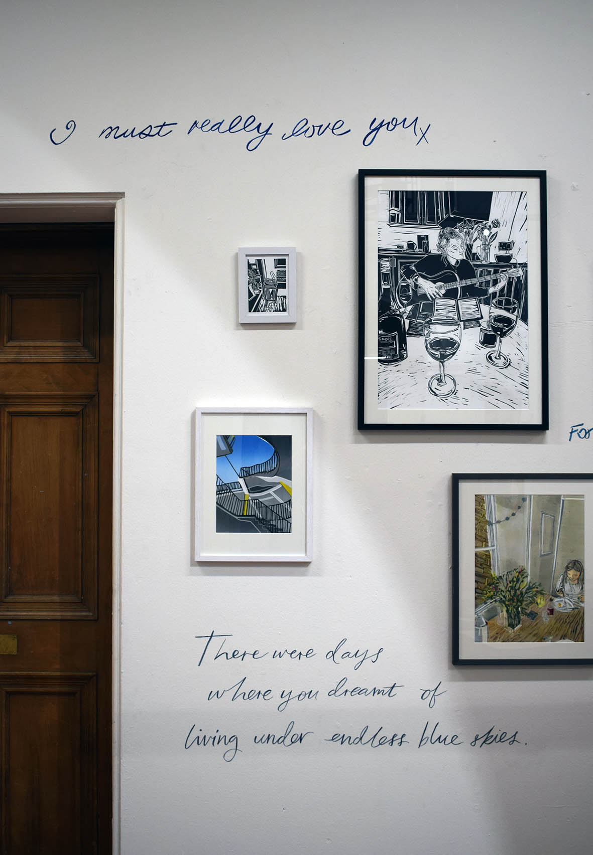 Framed prints surround handwriting on the wall 