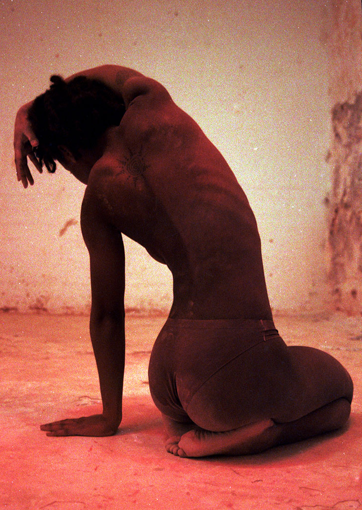 Photograph of woman kneeling with her arm stretched over her head