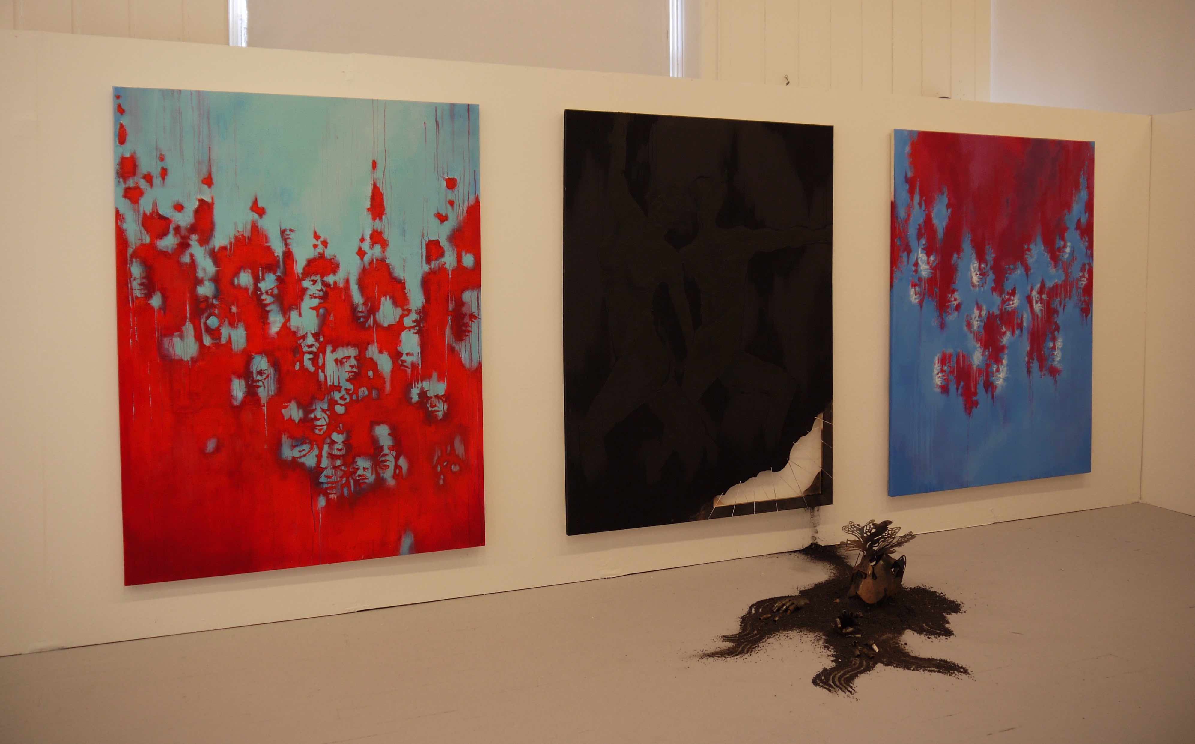 Three paintings with different colour schemes are installed from left to right. The central painting is entirely in black.. A sculpture is on the floor in front of the central black painting.