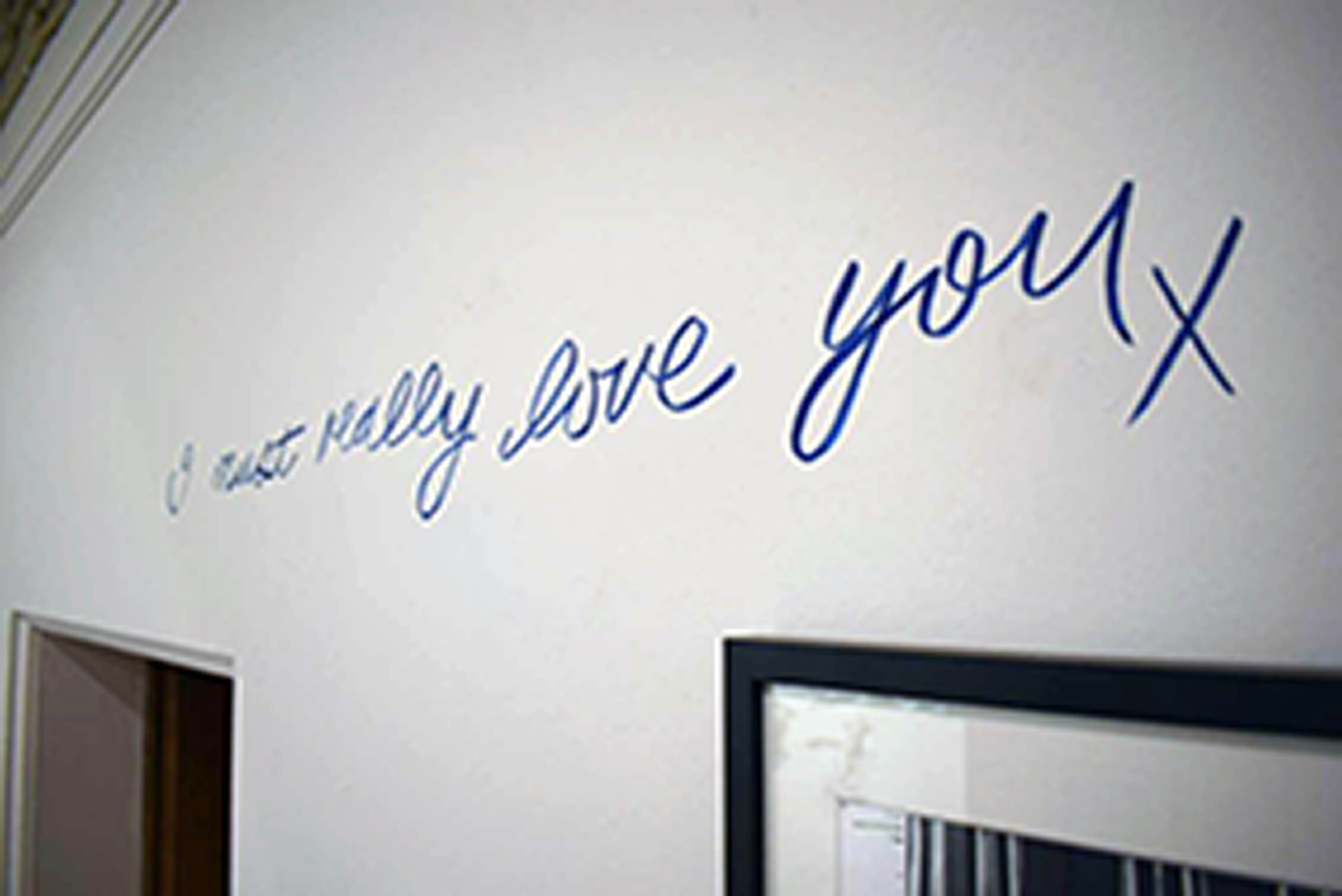 Handwriting reads 'I must really love you' on the wall above the door
