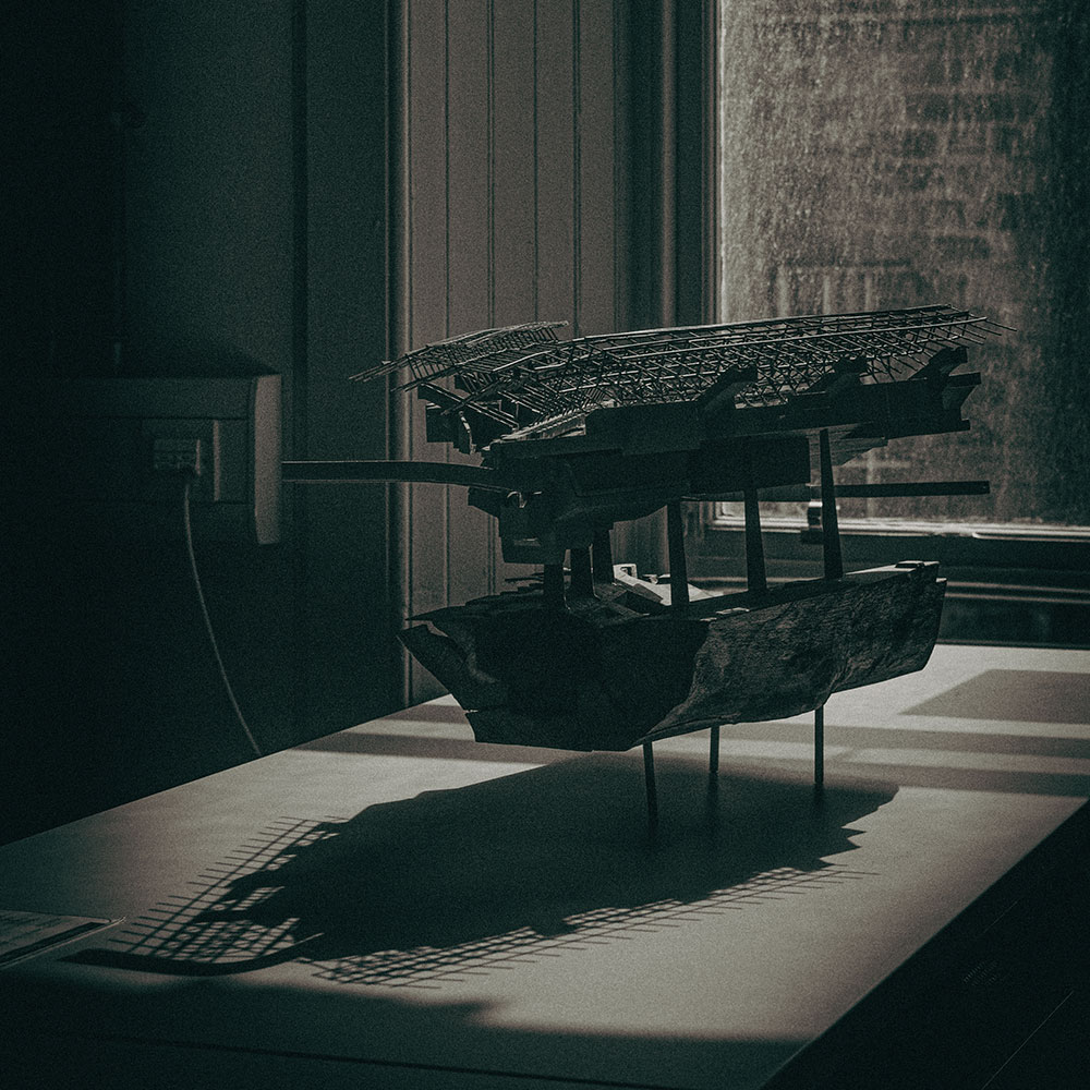 An architect's model on sticks on a table, casting a shadow.