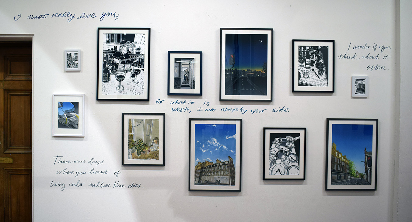 Framed prints surround handwriting on the wall 