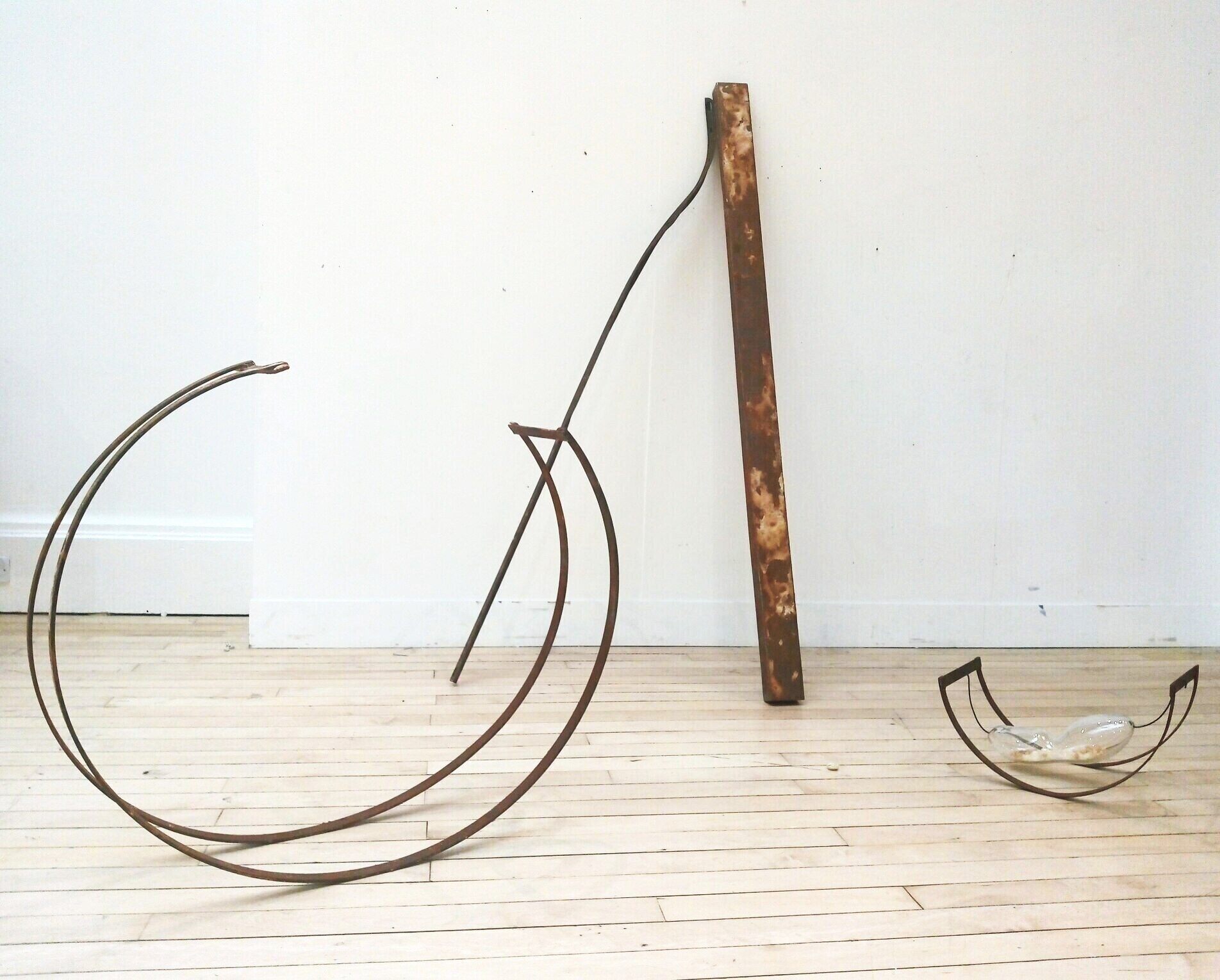 Arrangement of rusted metal bars, circular shape and semi-circular shape containing glass flask