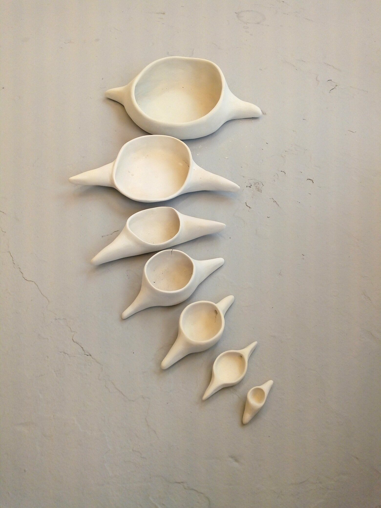 A line of white ceramic vessels resembling vertebrae