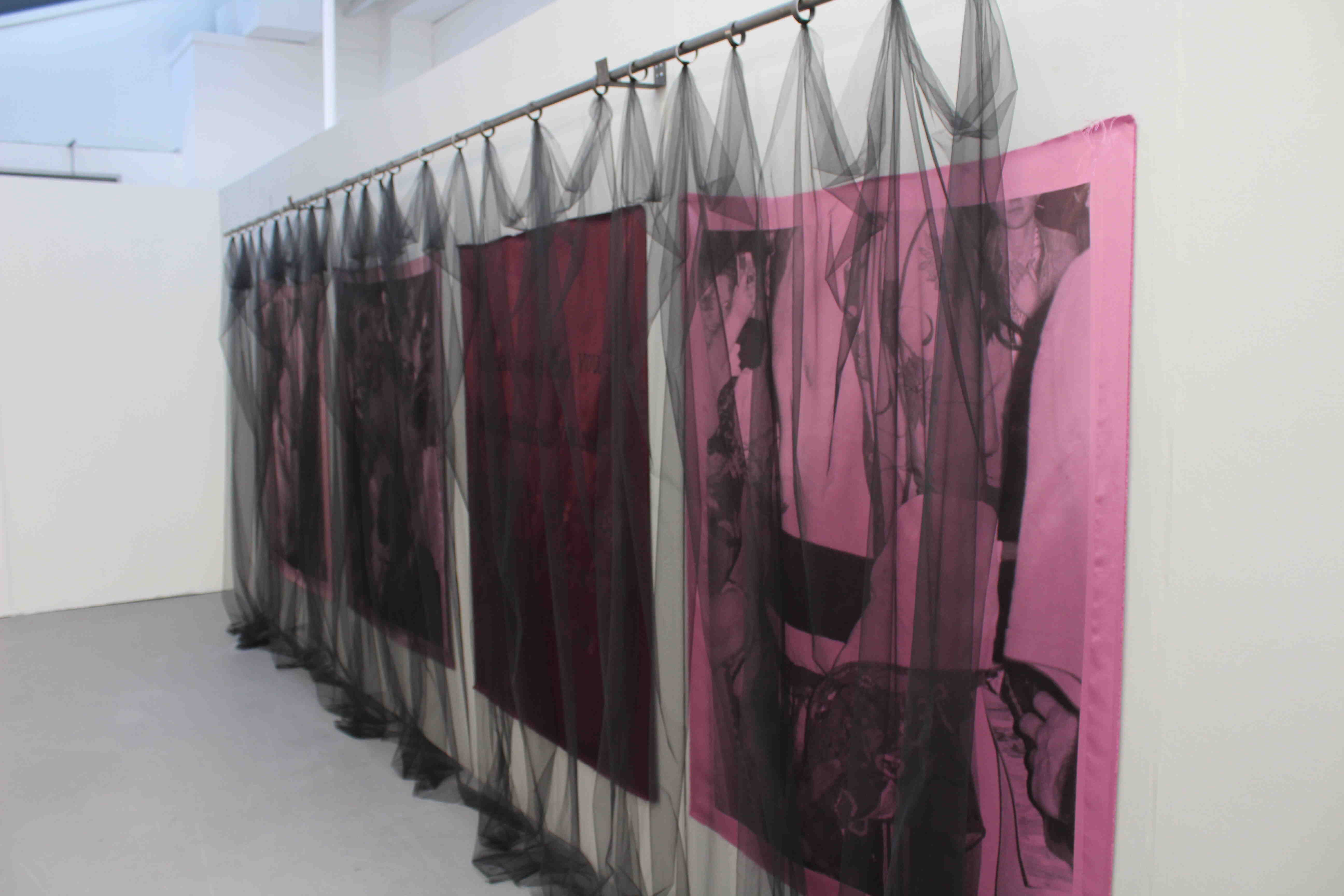 4 fabric ahngings on a wall. all pink and purple in colour. three have balck and white club photos printed on and one has hand painted text reading: what veils do you place between yourself and the things you do not have the words for. In front there is a black mesh veil hanging from an iron curtain rod.