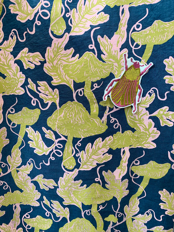 Embroidered beetle patch on mushroom printed fabric
