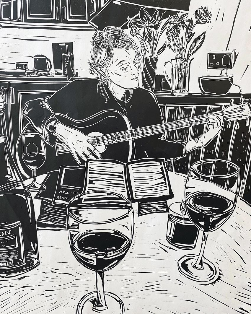 A woman sits a a table playing the guitar 