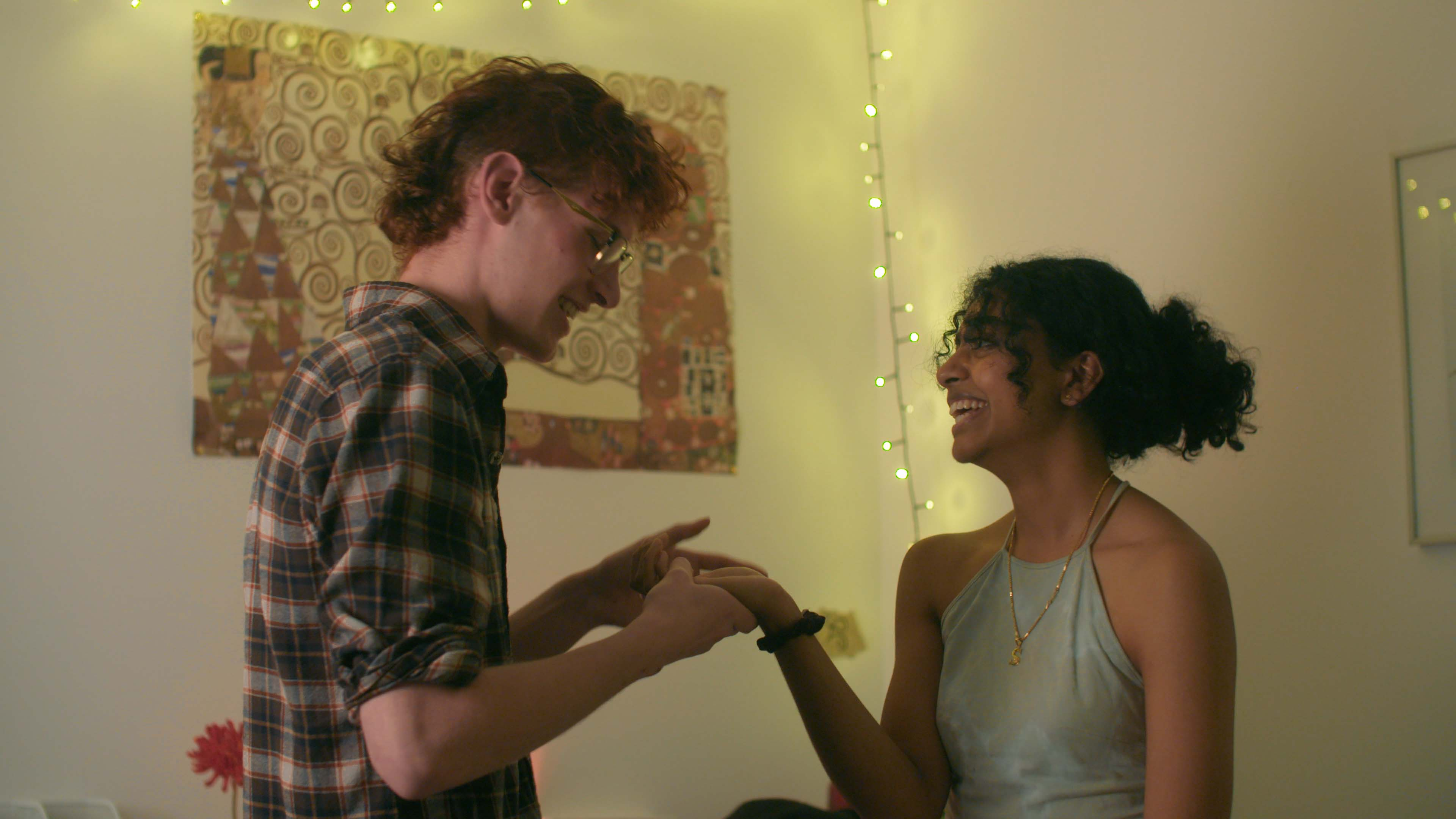 A boy holds the hand of a girl. She's laughing