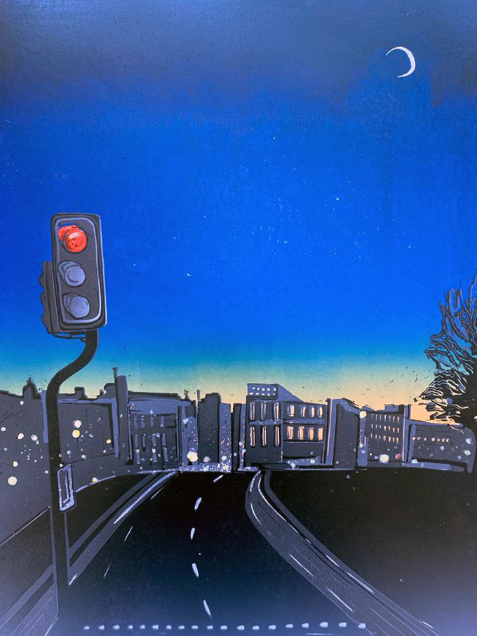 Cityscape at dusk. The last of the light can be seen on the horizon. The moon is high in the sky and the traffic light turns red.