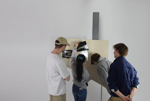 Photo of full scale segment, with four people looking at it