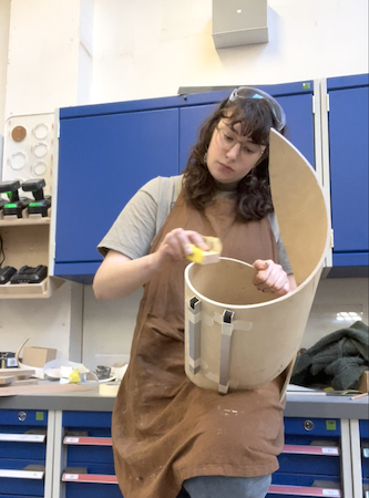 Katherine is sanding down the edges of the wooden spiral 