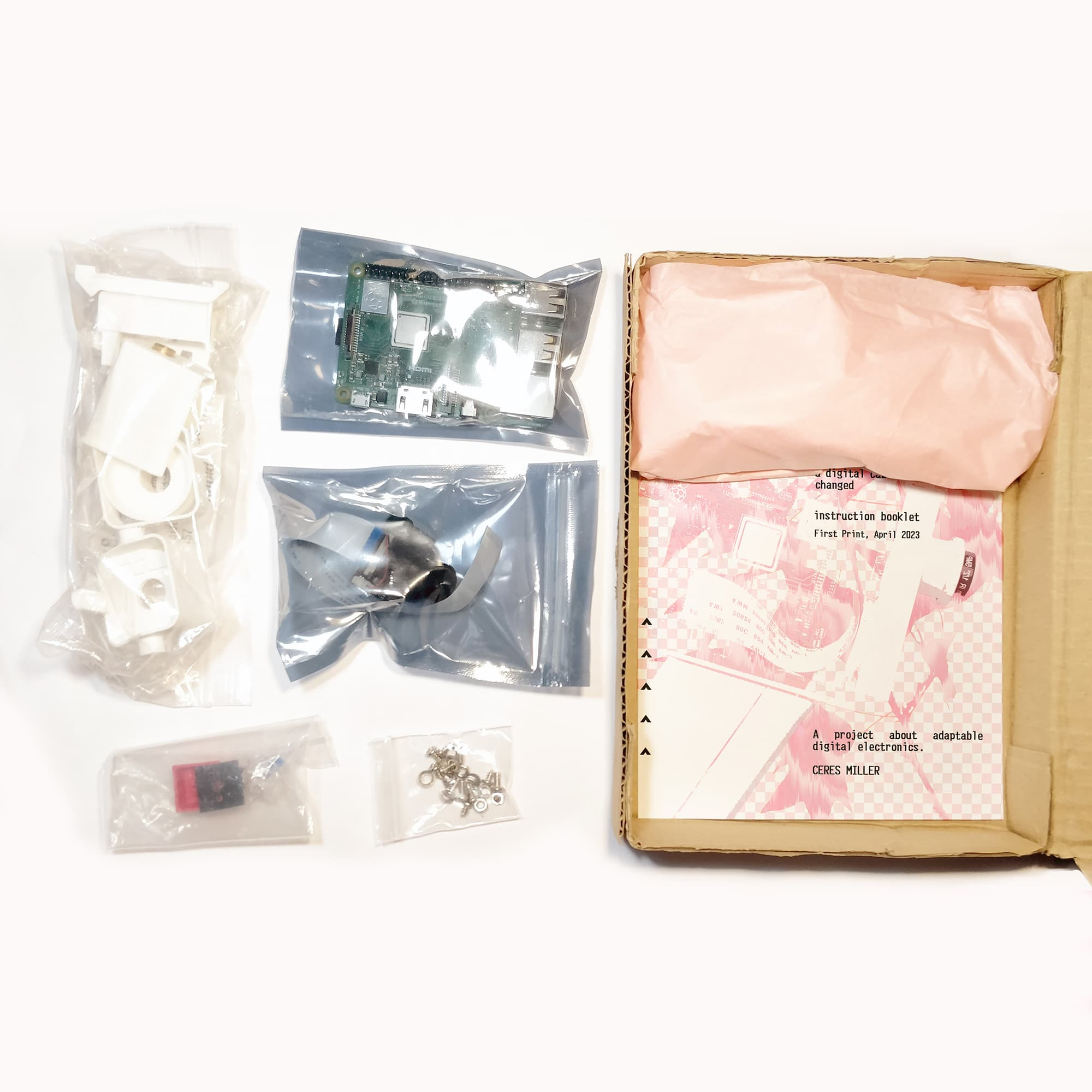 Camera parts in a packaging box, pieces in little bags, the brass parts wrapped up in tissue paper